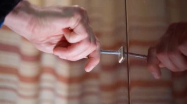 The hand inserts the key into the lock of the wooden cabinet door and turns it trying to open it. The key is stuck in a vintage lacquered door. Trying to open old vault. High quality 4k footage