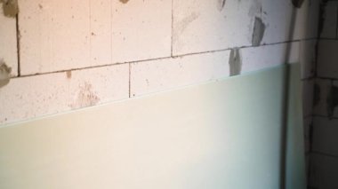 Sheet of drywall stale on the wall from the gas block close-up. Smooth camera movement at a construction site. Moisture resistant drywall in a room without repair. High quality FullHD footage