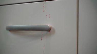 Red traces of blood on the facades of the kitchen close-up. Shelf handles in the kitchen are stained red. Smooth camera movement up. High quality FullHD footage