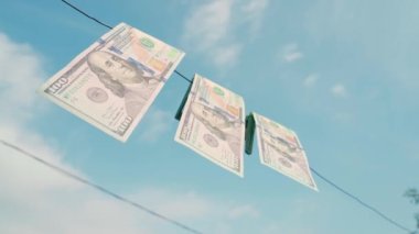 Cash is drying on a clothesline against a blue sky. Three hundred dollar bills are pinned with clothespins on a wire close-up. Laundering of money. High quality 4k footage