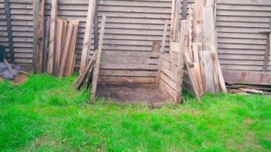 Disassembled wooden compost heap. Wooden frame for sorting organic biodegradable human waste. A lot of old wooden boards on the street on a green stave in summer. High quality FullHD footage