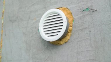 External round ventilation grill in the wall close-up. Air extract from the basement built into the wall with construction foam. Smooth camera movement. High quality FullHD footage