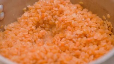 Orange lentils are cooked close-up, parallax. Cooking process by heat treatment of bean groats. High quality FullHD footage