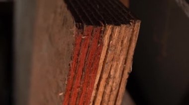 Oriented strand board with red paint against moisture. The edge of the OSB panel is treated with a red moisture-resistant composition, close-up. Smooth camera movement. High quality FullHD footage