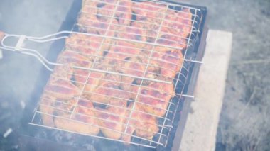 Chicken wings in a grid are fried on the grill in the smoke close-up, top view. High quality FullHD footage