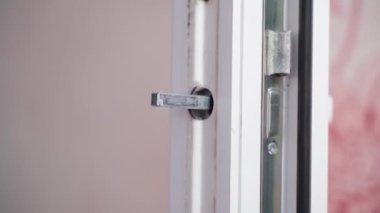 Fastening the door handle of a white plastic door close-up on a blurred background. High quality FullHD footage