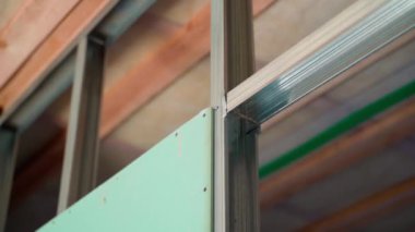 Moisture-resistant green drywall screwed to a metal profile frame close-up on a blurred background. Smooth parallax. High quality FullHD footage