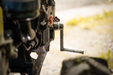 Elle kumandalı bir traktör motorunda, bulanık bir arkaplanda dizel motoru çalıştırmak için elle çalıştırıcı. Eğri marş, mini bir traktörden sarkıyor.