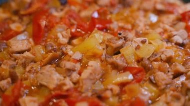 Vegetable stew with bell pepper and chicken is being prepared close-up. Vegetables and meat are fried in oil, smooth parallax. High quality FullHD footage