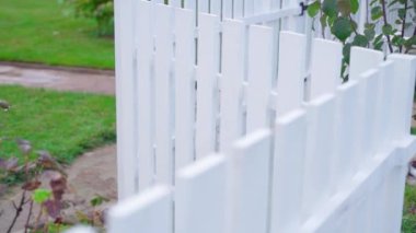 Beautiful neat wooden fence of white color is low. A small fence on a private plot with your own hands. Smooth parallax camera movement. High quality FullHD footage
