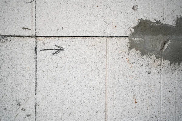 The line is drawn on a bare aerated concrete wall and the arrow is close-up. Drawn arrow at a construction site, copyspace