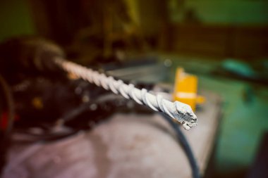 The tip of a spiral drill for concrete for a hammer drill close-up on a blurred background. Tool for drilling holes in reinforced concrete walls