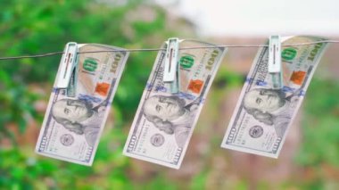 Cash laundering. Three hundred dollars drying on a clothesline pinned with clothespins close-up on a blurred background, smooth parallax. High quality FullHD footage
