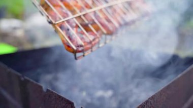 Flipping the grid with chicken wings cooking on the smoke on the grill close-up on a blurred background. Cooking meat on charcoal. High quality FullHD footage
