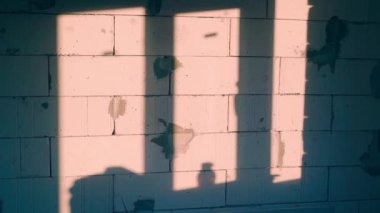 The evening setting sun falls through the window onto the wall of aerated concrete bricks. A bare gas-block wall in the shade. Smooth camera glide. High quality FullHD footage