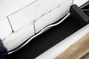 Corrugated pipe with a wire laid near the wall of aerated concrete block. Laying electrical wiring when building a house. Broken cable in plastic protection
