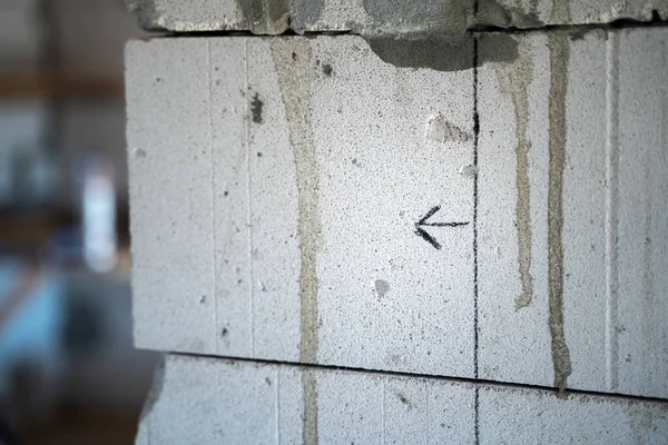 An arrow drawn with a pencil on a gas block wall close-up. The line drawn on the wall of aerated concrete bricks for builders. Clarification when repairing a private house. direction symbol