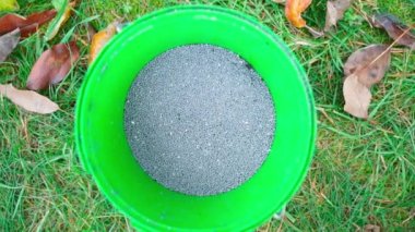 Granular soil fertilizer in gray color in a bucket close-up. Superphosphate for feeding the soil of trees in autumn. High quality FullHD footage