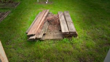 Temeli attıktan sonra eski tahtalar ve demir parmaklıklar yeşil çimlerin üzerine uzanıyor. Formaliteler ve takviye çalışmalarının ardından arta kalanlar. Özel bir mülkte inşaat atığı. Yüksek kalite FullHD