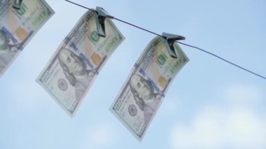 Dolarlar mavi gökyüzüne yakın planda mandallarla tutturulmuş. Yüksek kaliteli FullHD görüntüler