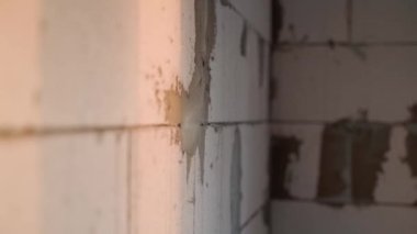 İnşaat alanında çıplak bir gaz bloğu duvarı, yakın plan. Havalı beton tuğlalardan yapılmış tuğla. Yarım kalmış özel bir evde gün batımı. Yüksek kaliteli FullHD görüntüler
