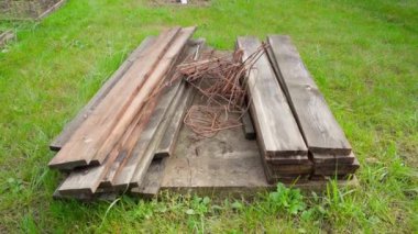 Sokaktaki ıslak tahtalar ve paslı demir çubuklar yeşil çimlerle çevrilidir. Formalite ve takviye çalışmalarından sonra kalıntılar. Kamera inşaat atıklarının üzerinde sorunsuzca uçuyor. Yüksek