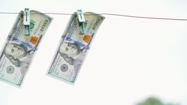Yüz dolarlık banknotlar, gökyüzüne karşı yakın plan mandallarla tele bağlanıyor. Yüksek kaliteli FullHD görüntüler