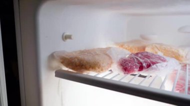 Kamera buzdolabının dondurucusuna doğru uçar. Ürünler şeffaf plastik poşetlere dolduruldu. Et ve mısır. Yüksek kaliteli FullHD görüntüler