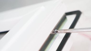 Plastik kapıdaki vidayı sökmek, yakın plan. Phillips tornavida vidayı söker. Beyaz plastik pencereyi söküyorum. Yüksek kalite 4k görüntü