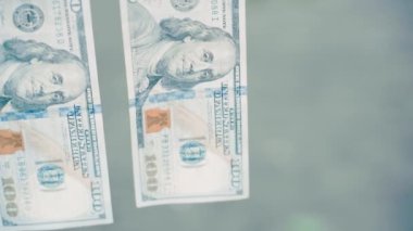 Mandallar yüz dolarlık banknotları kabloda, kasvetli soğuk ışıkta tutar. Yakın plan, bulanık arka plan, düzgün kamera hareketi. Yüksek kaliteli FullHD görüntüler
