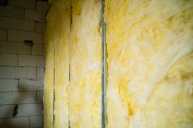 The partition is filled with glass wool. Frame wall from a metal profile with mineral wool close-up. Freshly built interior partition in a private house clipart