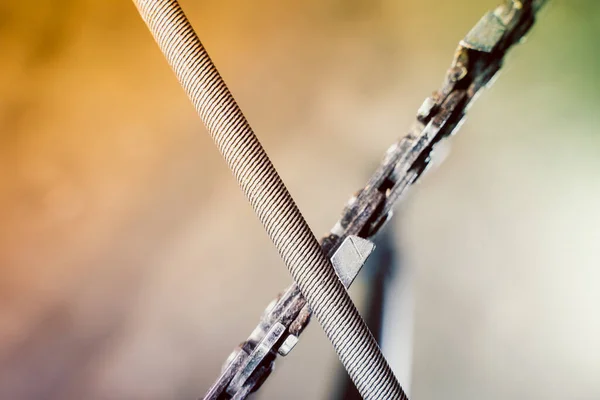 A round file sharpens a saw chain on a chainsaw bar close-up on a blurred background
