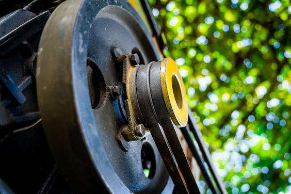 Driven pulley of a walk-behind tractor with two belts close-up on a blurred background. Small Tractor Engine for Garden Tillage