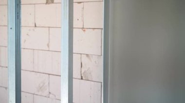 Metal U profili ve havalandırmalı beton duvar. Metal profil ve gaz bloğundan yapılmış çerçeve duvarı. Tamamlanmamış özel bir evde tamiri olmayan çıplak duvarlar. Yüksek kaliteli FullHD görüntüler