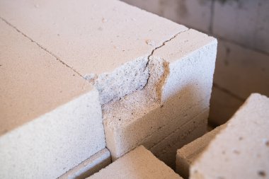 Çatlamış, yeni havalandırılmış beton kaplama yakın plan. Kırık bir parçayla beyaz gözenekli tuğla, kırılgan yapı malzemeleri.