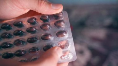 Eller yakın çekim sırasında büyük kahverengi bir hapı sıkıyor. İlaç alma simülasyonu. Yüksek kalite 4k görüntü