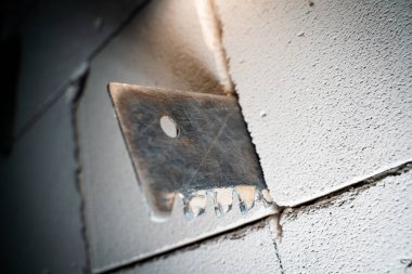 A hacksaw for aerated concrete sticks out of a wall of aerated concrete bricks close-up on a blurred background. Cutting a doorway in a gas block wall, handmade