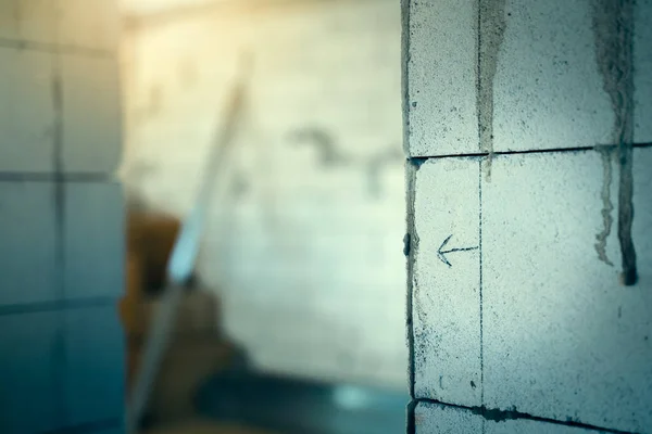 Stock image Copyspace at a house construction site against the background of an aerated concrete wall. The arrow painted on the wall of the gas block points in the direction of the doorway on a blurred background