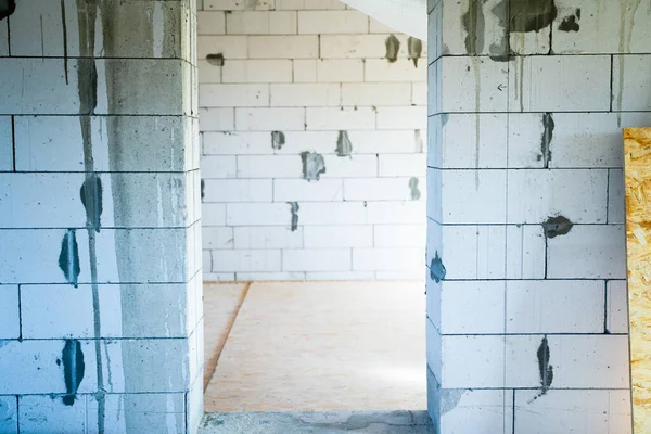 stock image Doorway in aerated concrete wall. Entrance to a room with bare walls made of aerated concrete bricks. Subfloor made of oriented strand board. Interior work in a newly built private house