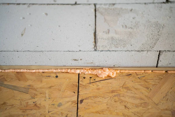The gap between the OSB slab floor and the aerated concrete wall is filled with construction foam. Hydrobarrier under a rough wooden floor