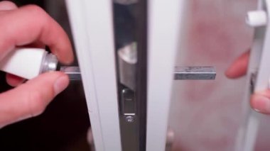 Plastik kapı kolunun tamiri, kırıldıktan sonra kapının restorasyonu. Beyaz plastik kapıya monte edilmiş, yakın plan. Yüksek kalite 4k görüntü