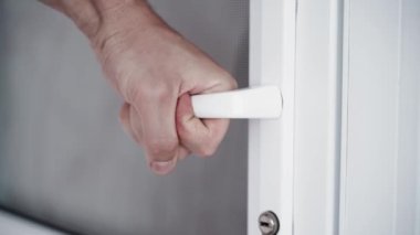 El sıkıca kapı kolunu sıkıyor ve gidiyor. Gergin adam, beyaz plastik bir kapının sapını tutuyor, yakın plan. Yüksek kaliteli FullHD görüntüler