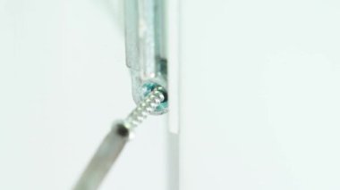 Bir Phillips tornavida, metal bir parçayı plastik bir kapının içine sıkıştırıyor, yakın plan. Yüksek kalite 4k görüntü