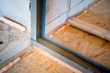 Alçıpan için çerçeve oluştururken metal bir profilin köşe bağlantısı. Tahta kirişlerle profilin uzunluğunu ayarlıyorum. Havalandırmalı beton duvarlar ve OSB levhalarının sert zemini.