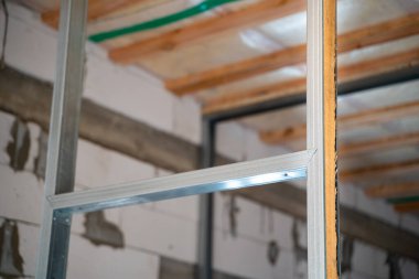 Kapı girişindeki ahşap kirişle metal profil çerçevesinin dayanıklılığını ve sağlamlığını güçlendiriyor. Alçıpan için bir metal profil oluşturuluyor