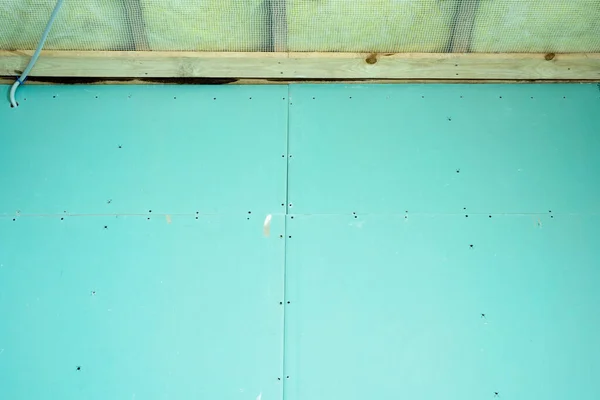 The frame wall is sheathed with blue moisture-resistant drywall