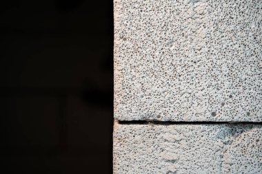 Koyu bir arka planda havalandırılmış beton bloğun bir kısmına yakın plan havalanan beton dokusu. Bir inşaat temasında tema alanı