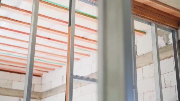 通気コンクリートブロックで作られた裸の壁で部屋に石膏ボードのシーリングのための金属プロファイルで作られたフレーム構造 高品質のフルHd映像 — ストック動画