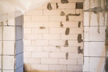 Arka taraftaki girişte çıplak beton duvar var. Odaya onarım yapılmadan giriliyor. Duvardaki çizilmiş ok tamamlanmadığını gösteriyor.