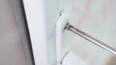 Kapı kolunu cıvata ve tornavidayla vidalamak, yakın çekim. Beyaz plastik kapı montajı ve montajı. Yüksek kalite 4k görüntü
